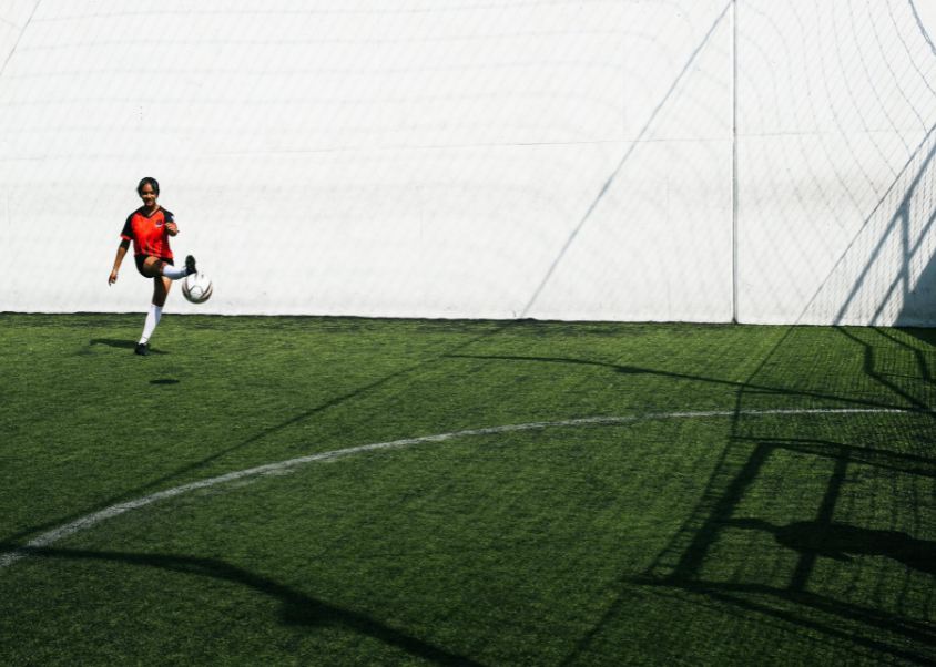 woman-soccer-player-kicking-ball-in-goal